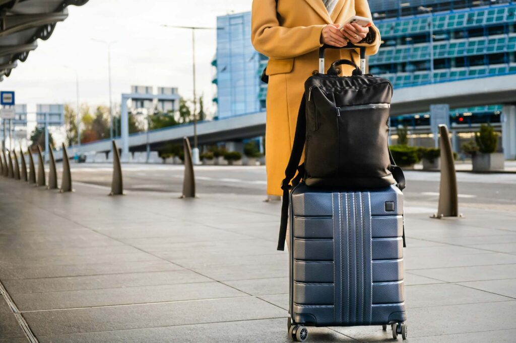 Woman Traveler In Coat With Handbag And Suitcase Orders Taxi 1024x682